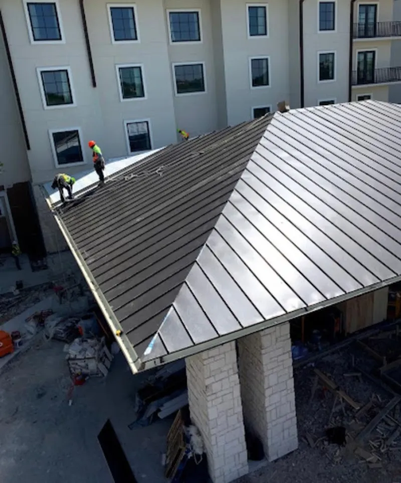 Crew installing standing seam metal roof panels on a commercial project in Old Lyme